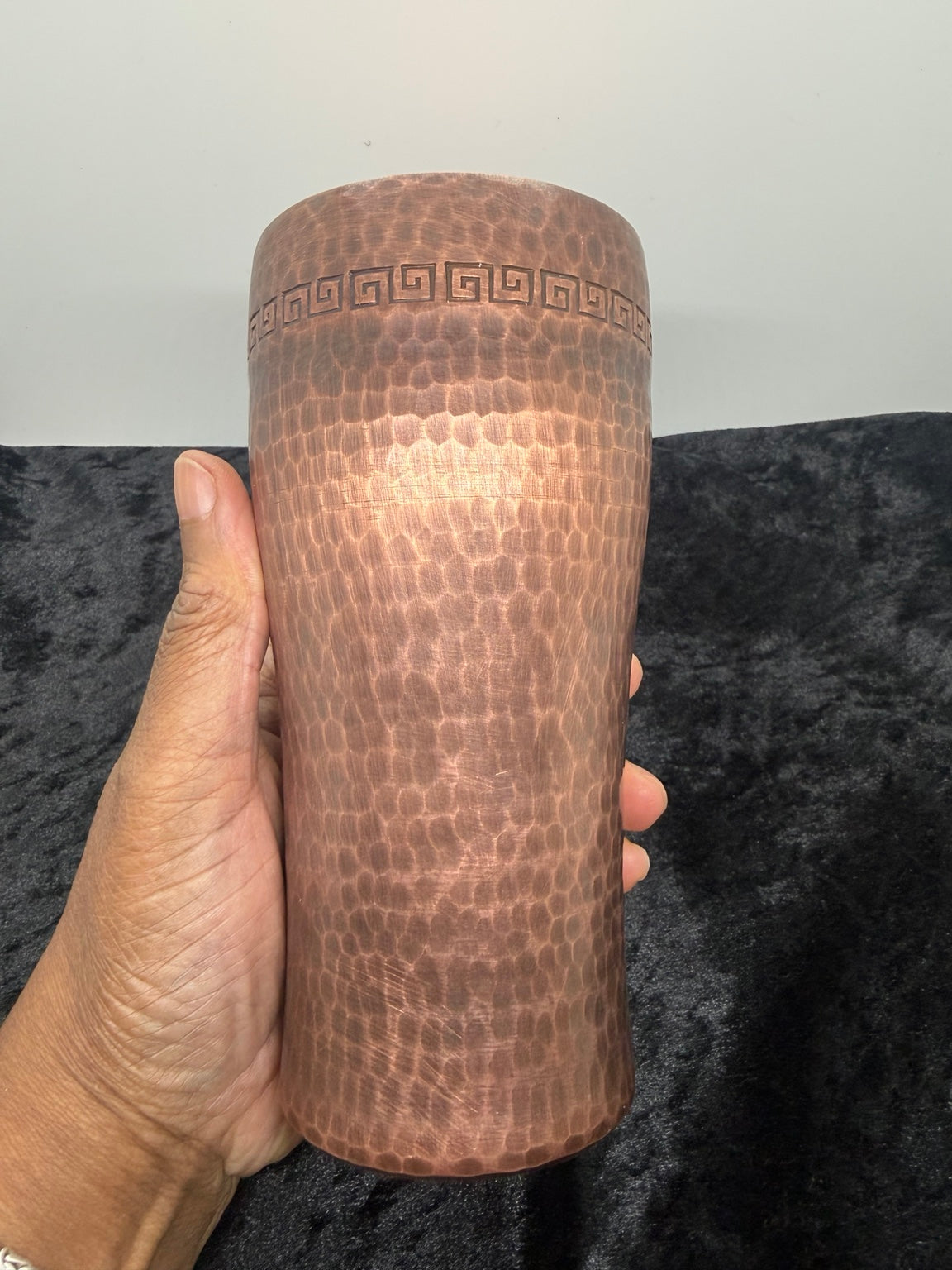 Antique hammered copper cup held in a hand