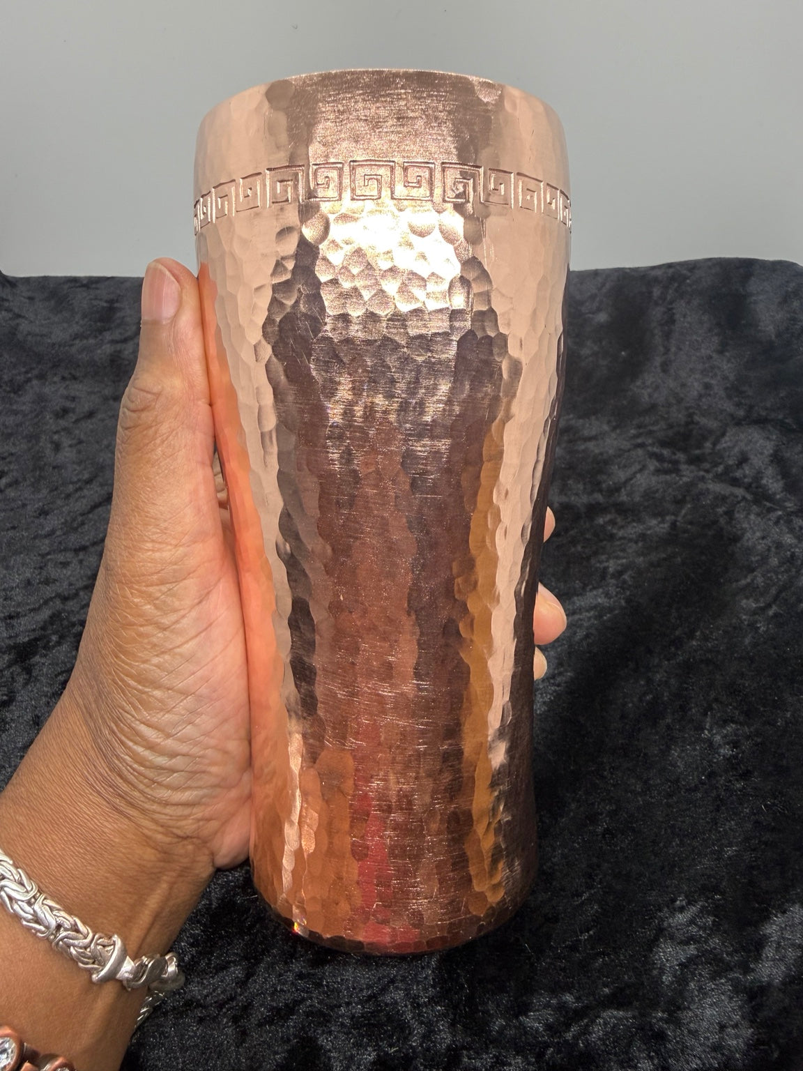 Bright hammered copper cup held in a hand