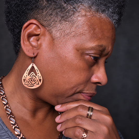 Sha wearing pure copper teardrop earrings against a clean studio background